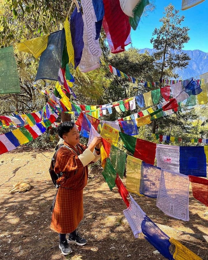 Monk among prayer flags on a Himalayan ridge