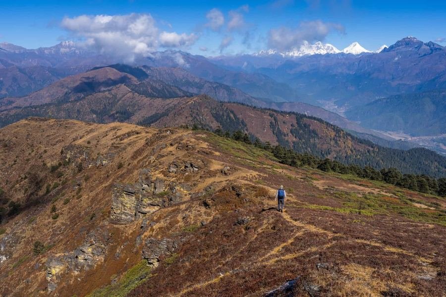 Trekker on the open ridge with Himalayan peaks beyond
