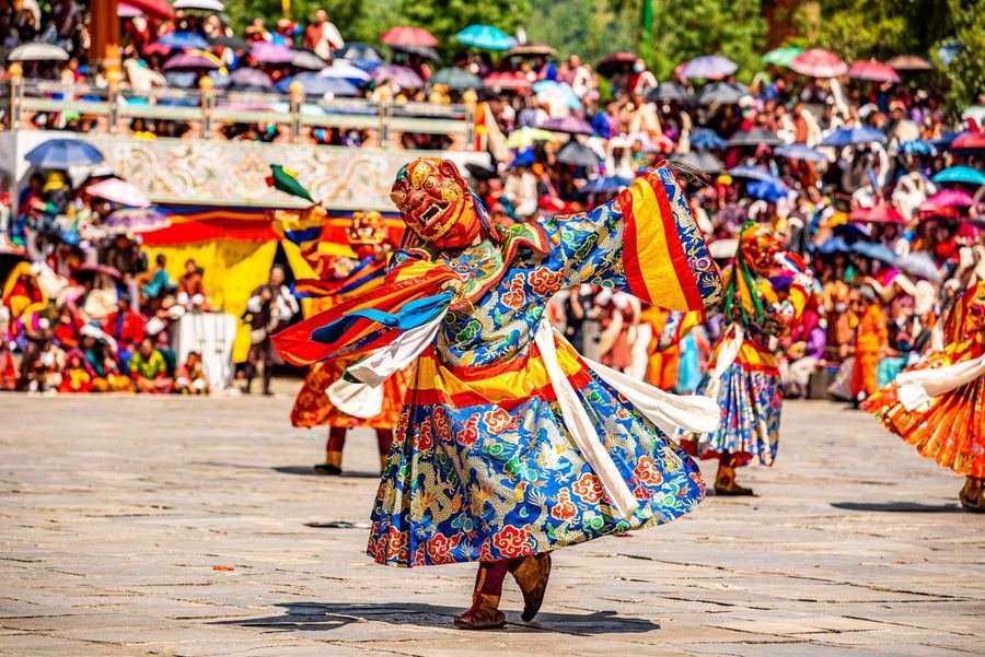 Masked cham dancers before a colourful festival crowd