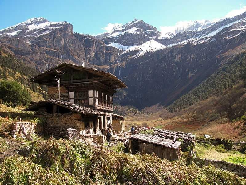 Traditional Bhutanese farmhouse with snow peaks beyond