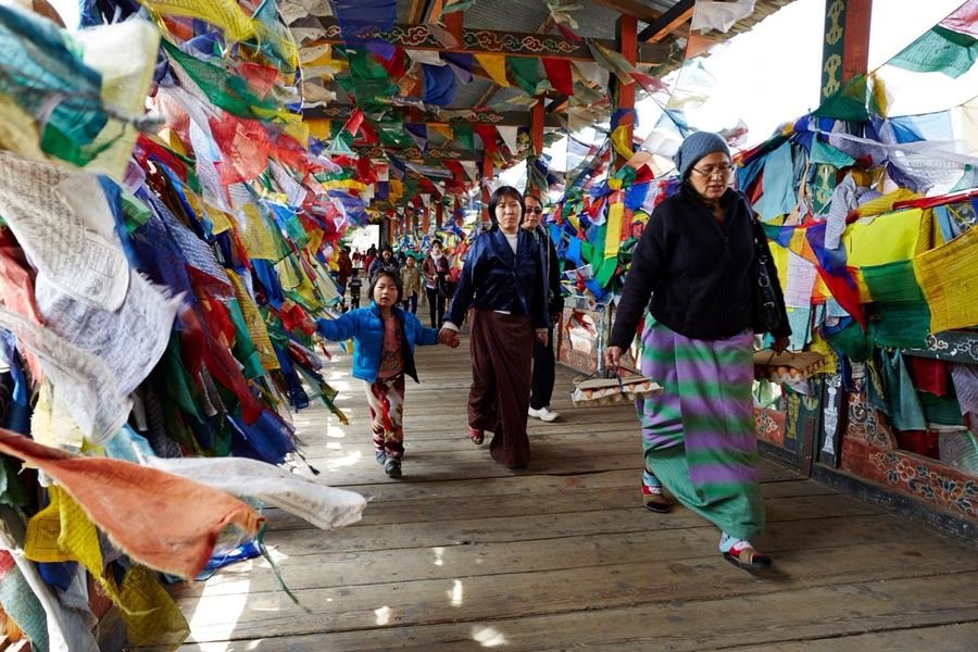 Visitors walking through an avenue of prayer flags