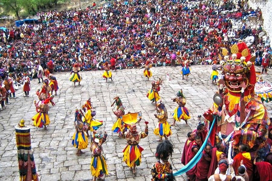 Masked dancers performing before a packed courtyard