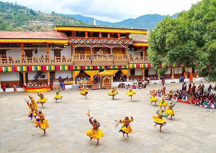 Yellow-robed dancers performing in the dzong courtyard
