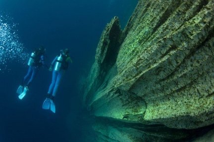 Pair of divers finning along the flank of a sunken hull