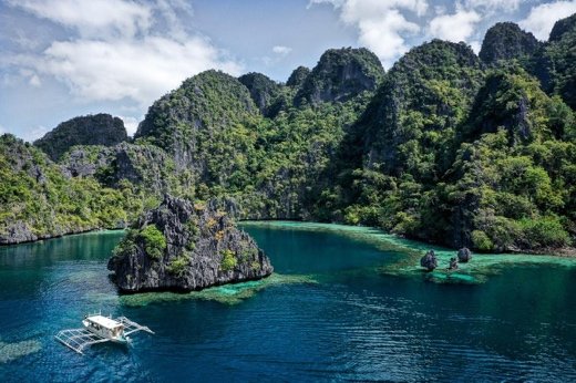 Bangka boat moored between towering limestone cliffs in Coron