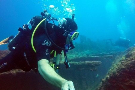 Diver close to the coral-covered plating of a sunken hull