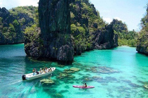 Boat and kayak on the emerald water of Big Lagoon between limestone cliffs