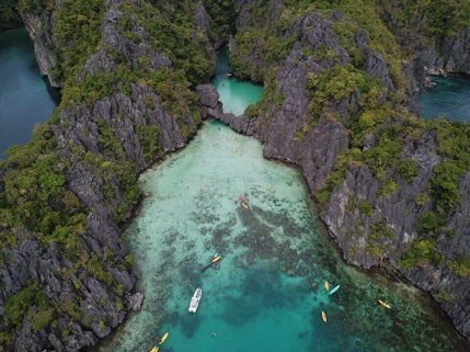 Aerial view of kayakers entering a hidden lagoon in Bacuit Bay