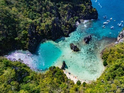 Aerial view of a secluded turquoise cove in Bacuit Bay