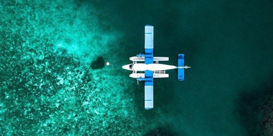 Overhead view of a seaplane crossing a shallow emerald reef