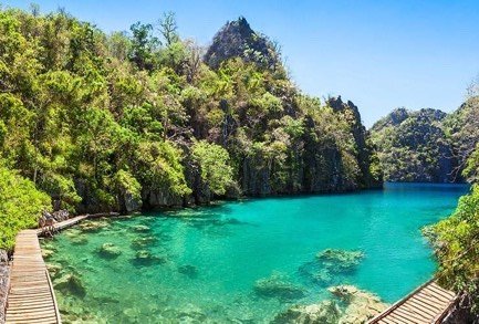 Wooden boardwalk beside the clear green water of Kayangan Lake