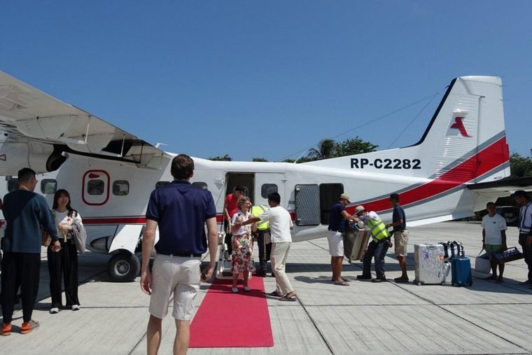 Guests boarding the Amanpulo private charter turboprop from a red carpet on the apron
