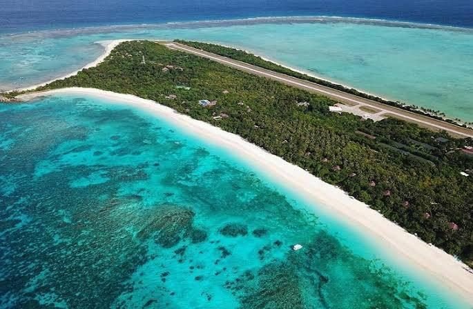 Aerial view of Pamalican Island's private airstrip running behind the beach and reef flats