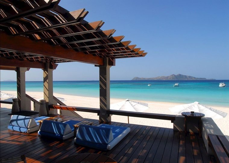 Shaded timber beach pavilion with day beds looking out to the turquoise lagoon