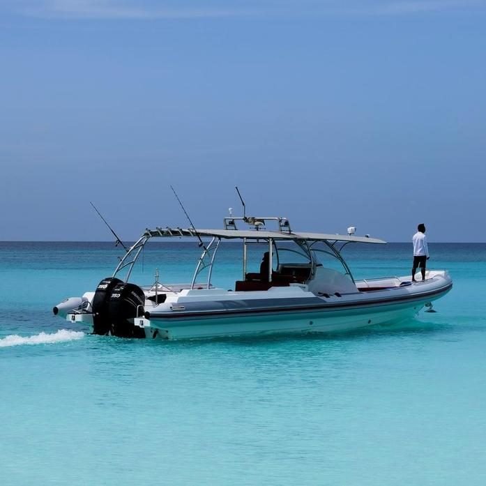 Private charter boat with twin outboards moored in shallow turquoise water off the island