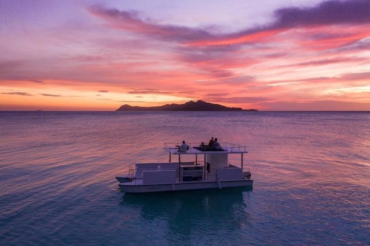 Private boat on a calm sea at sunset with an island silhouette on the horizon