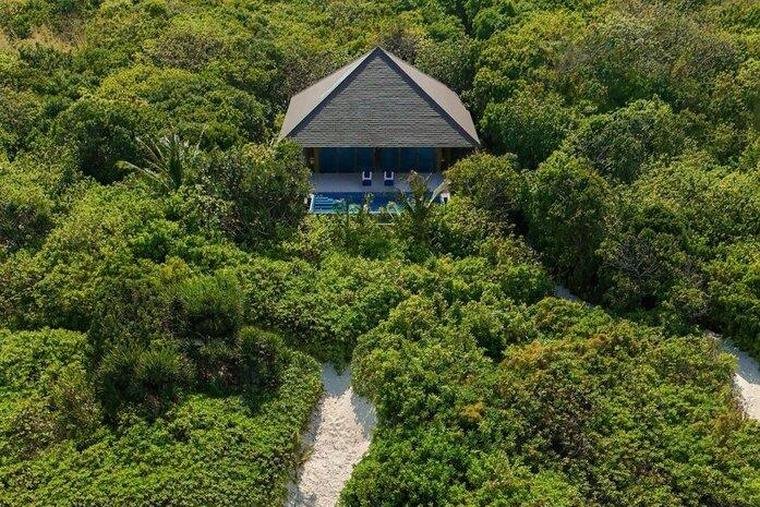 Aerial view of a beach casita and its pool set among dense greenery above the white sand