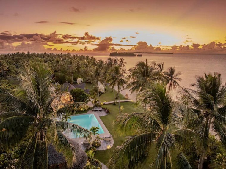 Resort pool and palm grove under a golden Siargao sunset