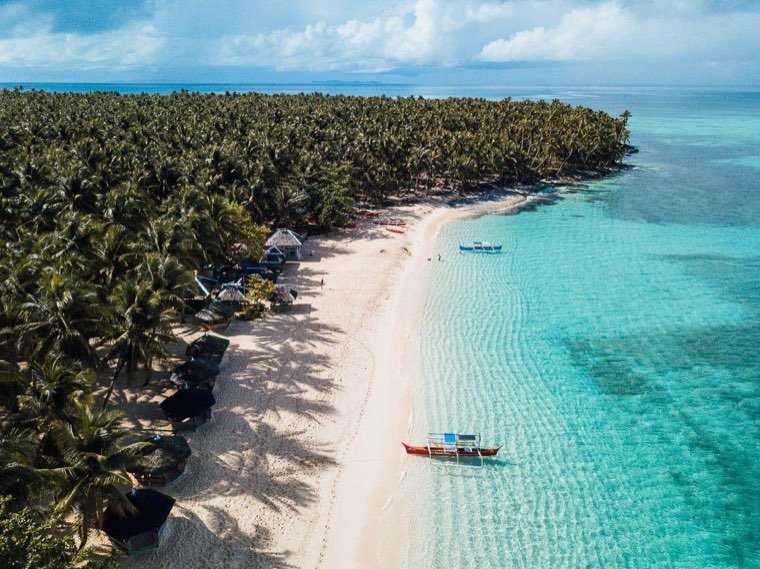 Curving palm-fringed shoreline and clear shallows on Siargao