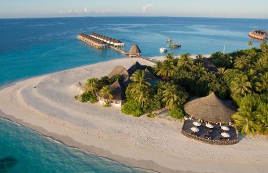Aerial view of Angaga Island Maldives showing its circular tropical layout, overwater villas, and surrounding blue lagoon.