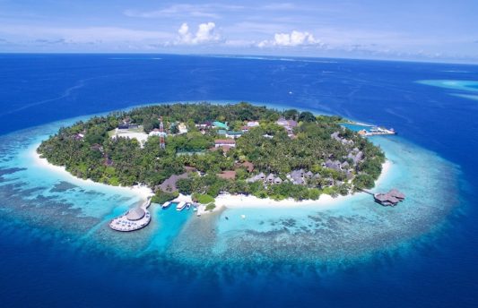 Aerial view of Bandos Maldives Resort & Spa in North Malé Atoll, showcasing lush tropical island surrounded by white sand beaches, overwater spa, and turquoise lagoon.