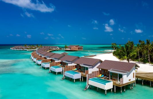Aerial view of Atmosphere Kanifushi Maldives luxury resort in Lhaviyani Atoll, featuring overwater villas.